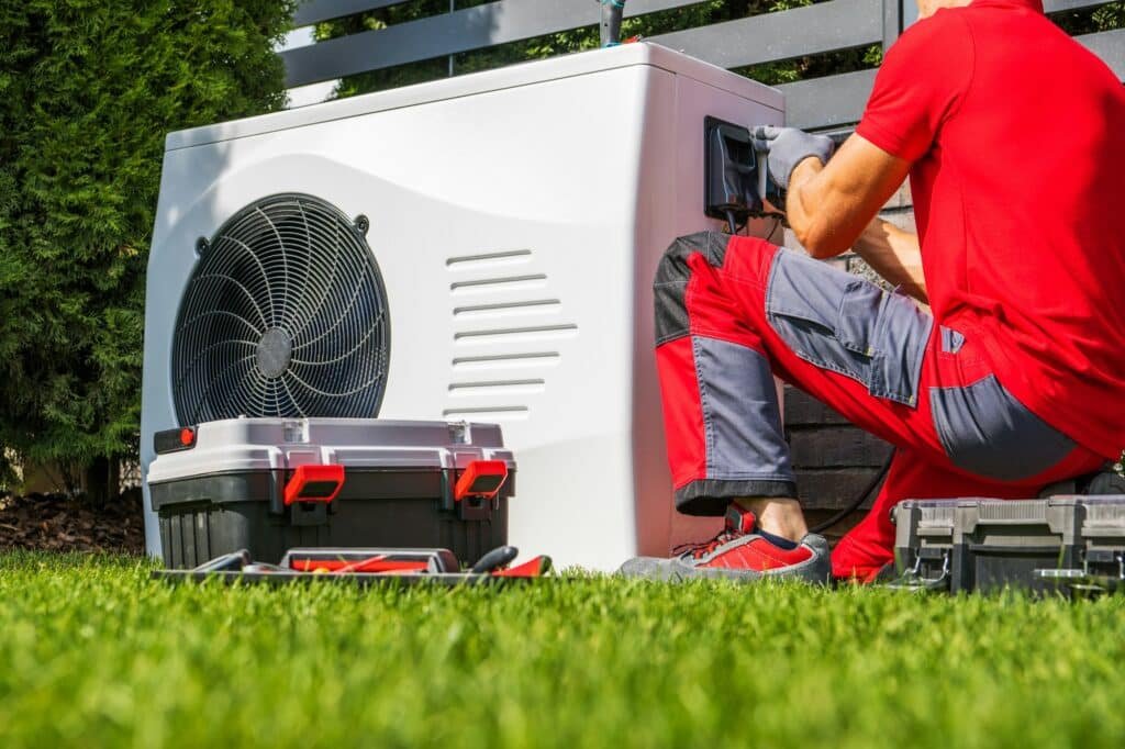 Technicien effectuant l'installation d'une pompe à chaleur extérieure dans un jardin