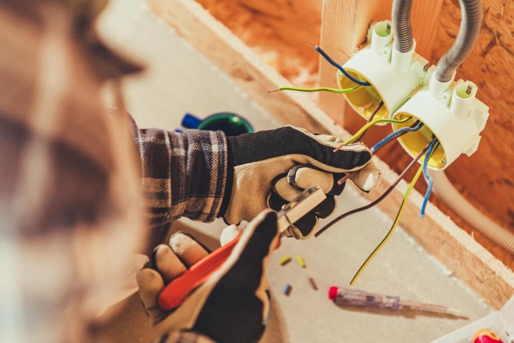 technicien tirant des câbles dans un mur pour installation électrique à Cabourg