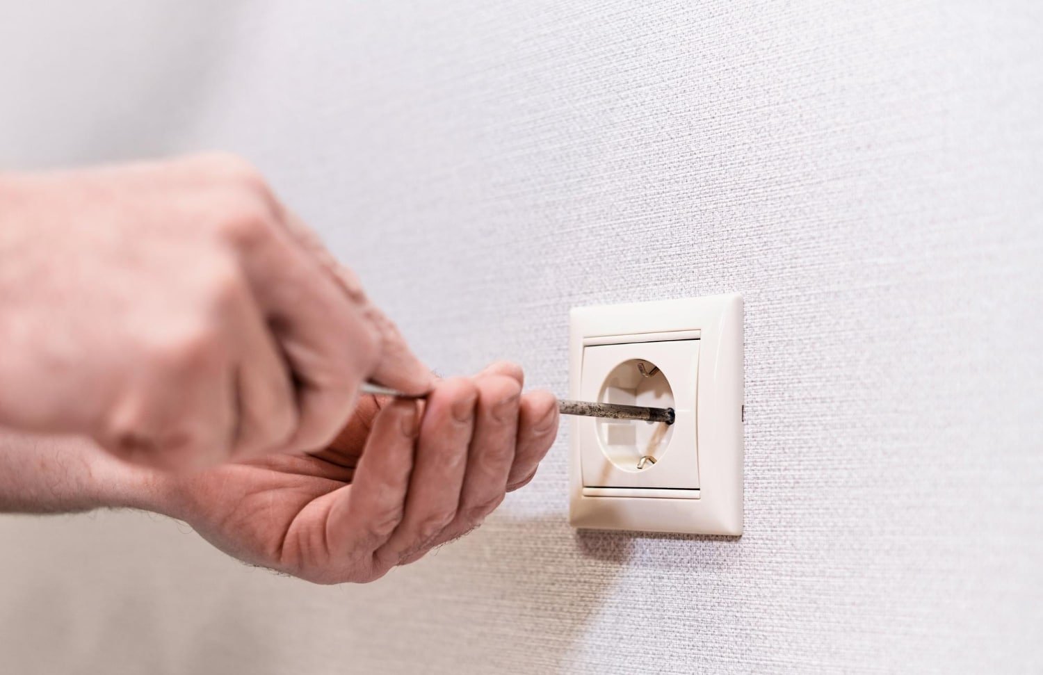 main insérant une prise dans une prise murale à Cabourg