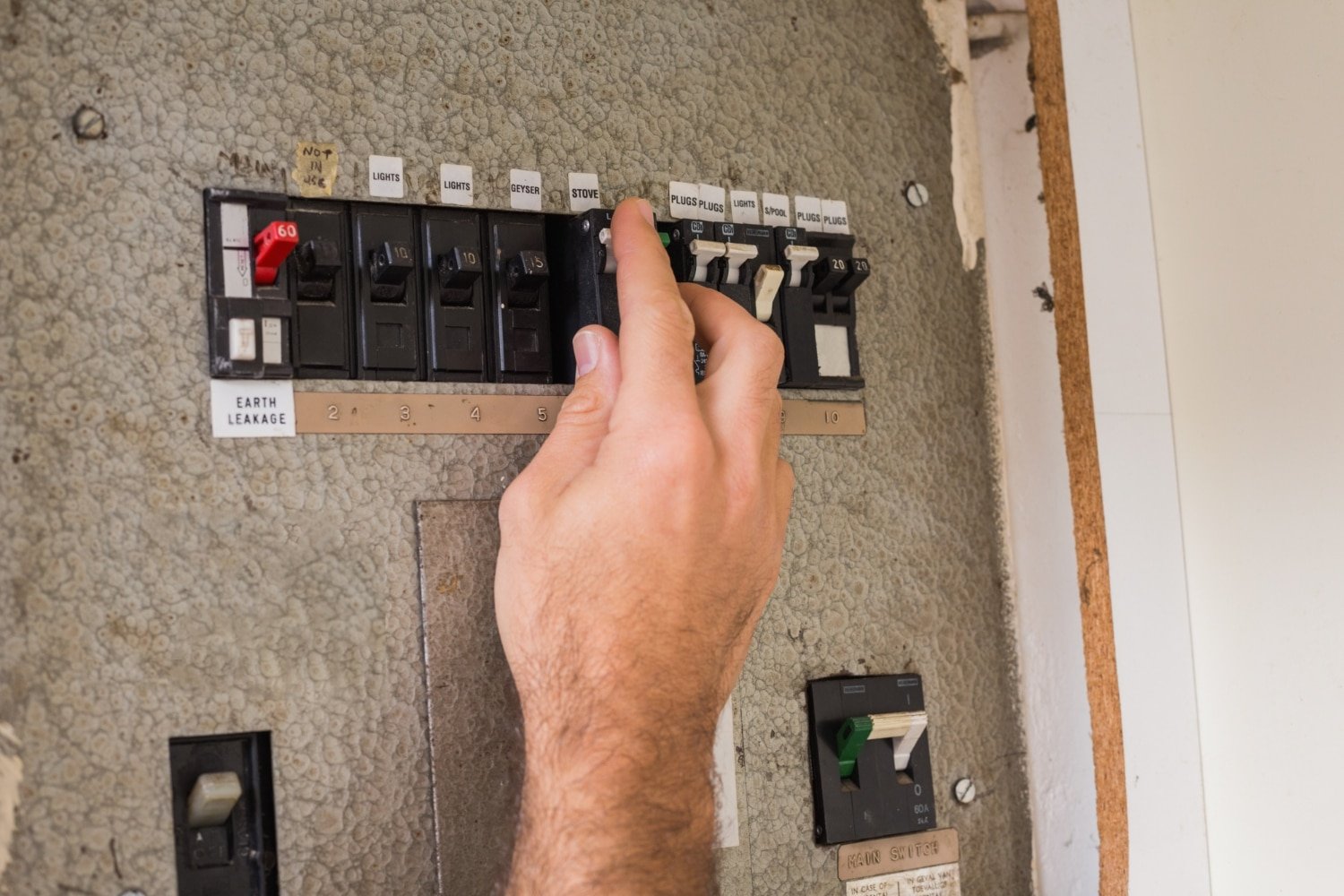 main activant un disjoncteur dans un tableau à Cabourg