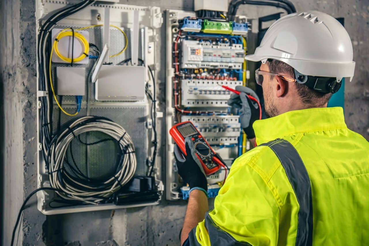 électricien en gilet jaune réalisant un test dans un environnement industriel à Cabourg