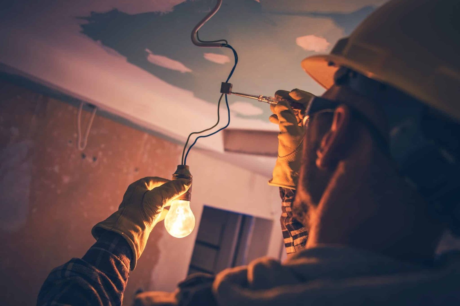électricien montant une ampoule suspendue sur chantier à Cabourg